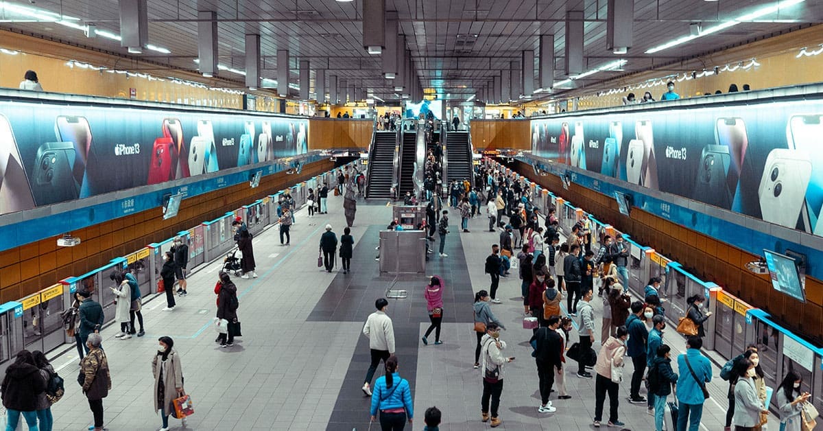 A crowded public transportation station featuring transit ads